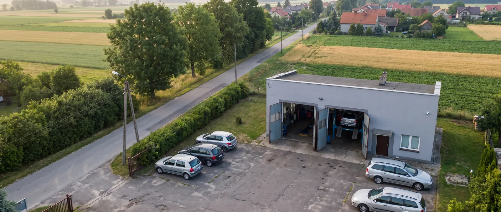 Niezależny warsztat samochodowy wśród pól, widok z drona